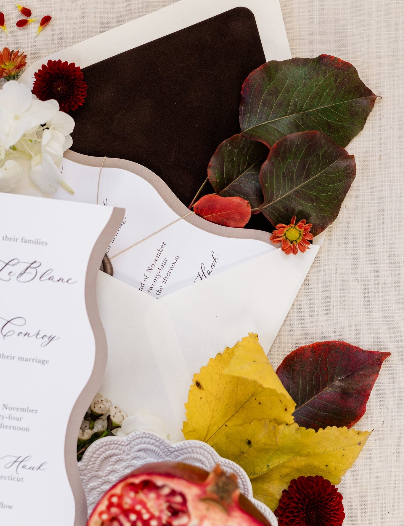 A close up of a dark brown velvet envelope liner.  Colorful leaves with deep greens and reds have been placed inside the envelope..