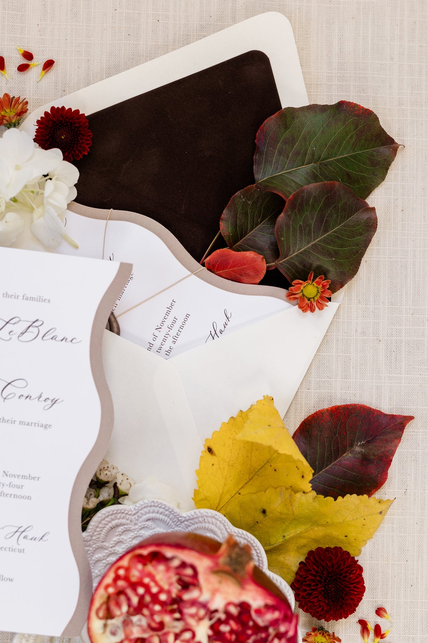 A close up of a dark brown velvet envelope liner.  Colorful leaves with deep greens and reds have been placed inside the envelope..
