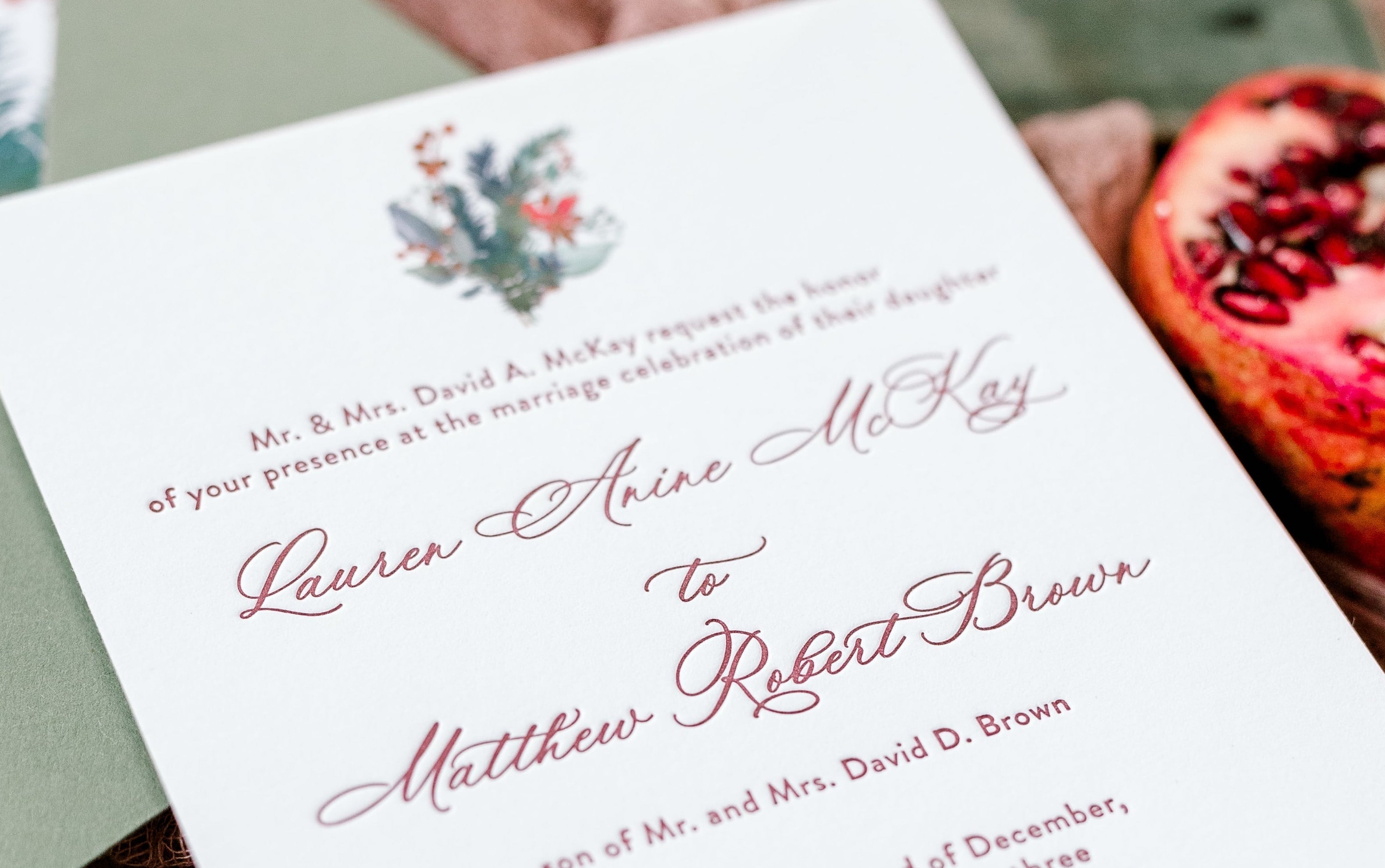 A close up of the lettering on an invite card. The text is letter pressed in a deep red ink.