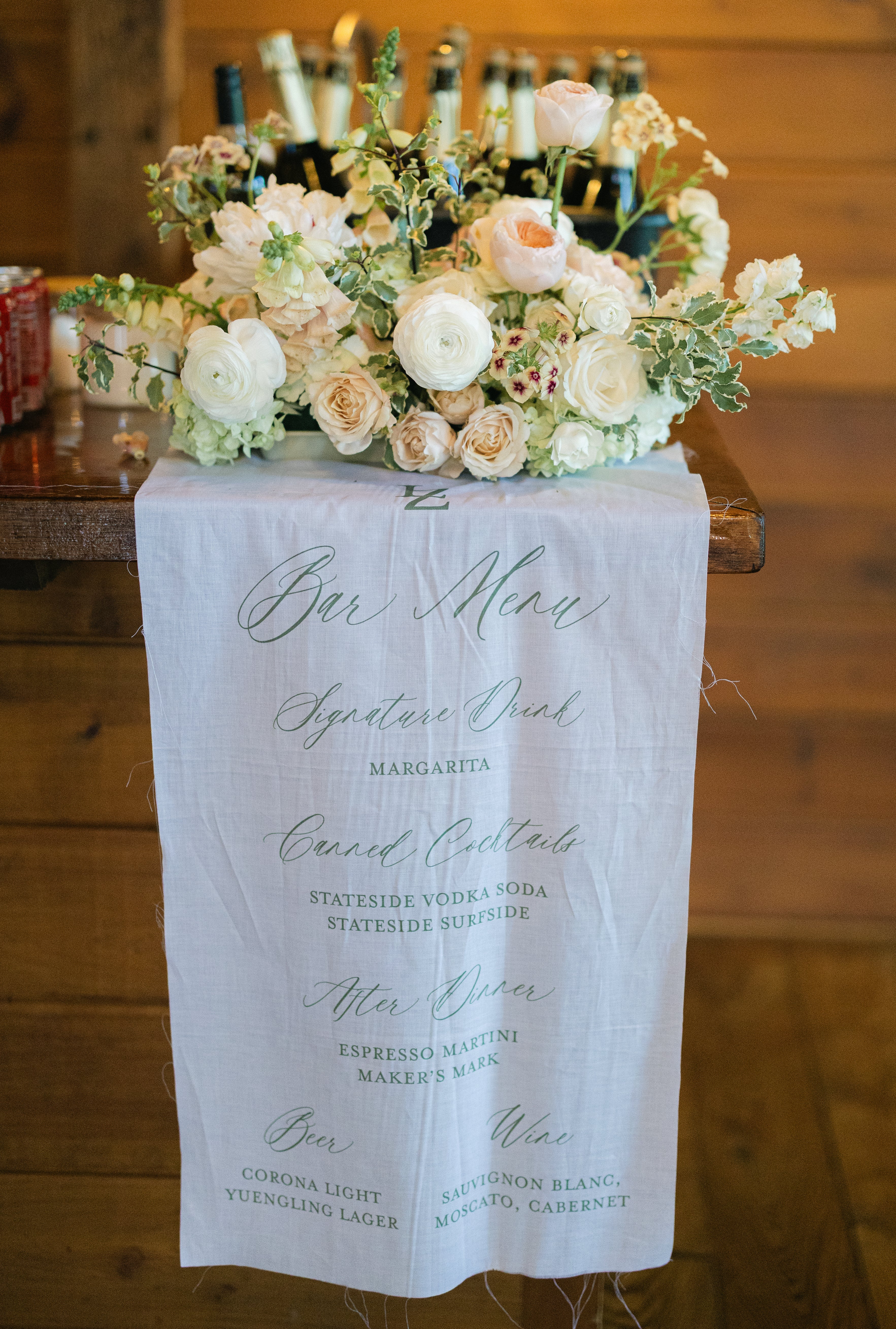 Decorative floral arrangement on a wooden surface with a menu in the foreground.