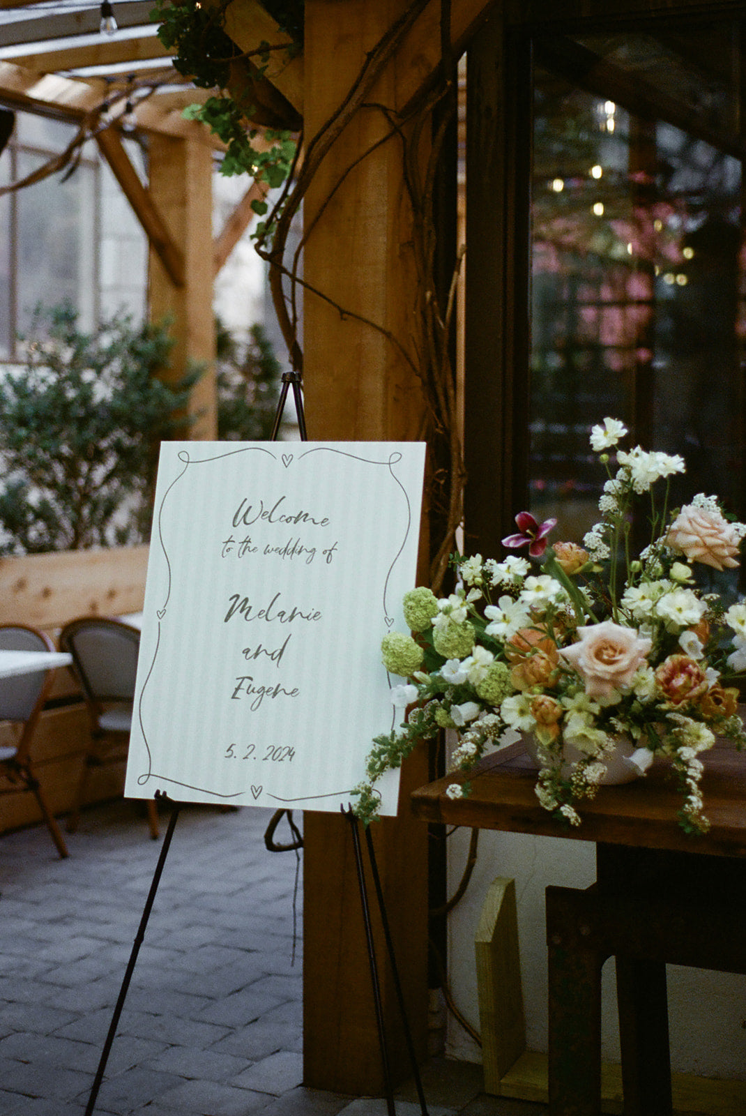 foamboard wedding welcome sign with green stripes and green script font on easel with floral arrangement