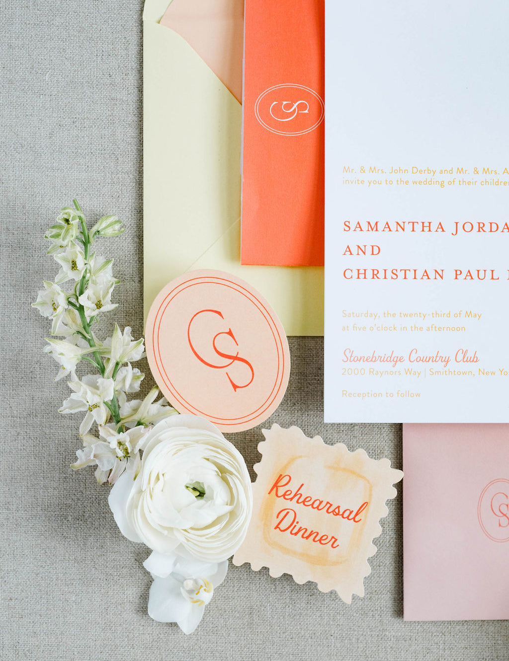 Wedding invitation set with flowers and seals on a gray surface