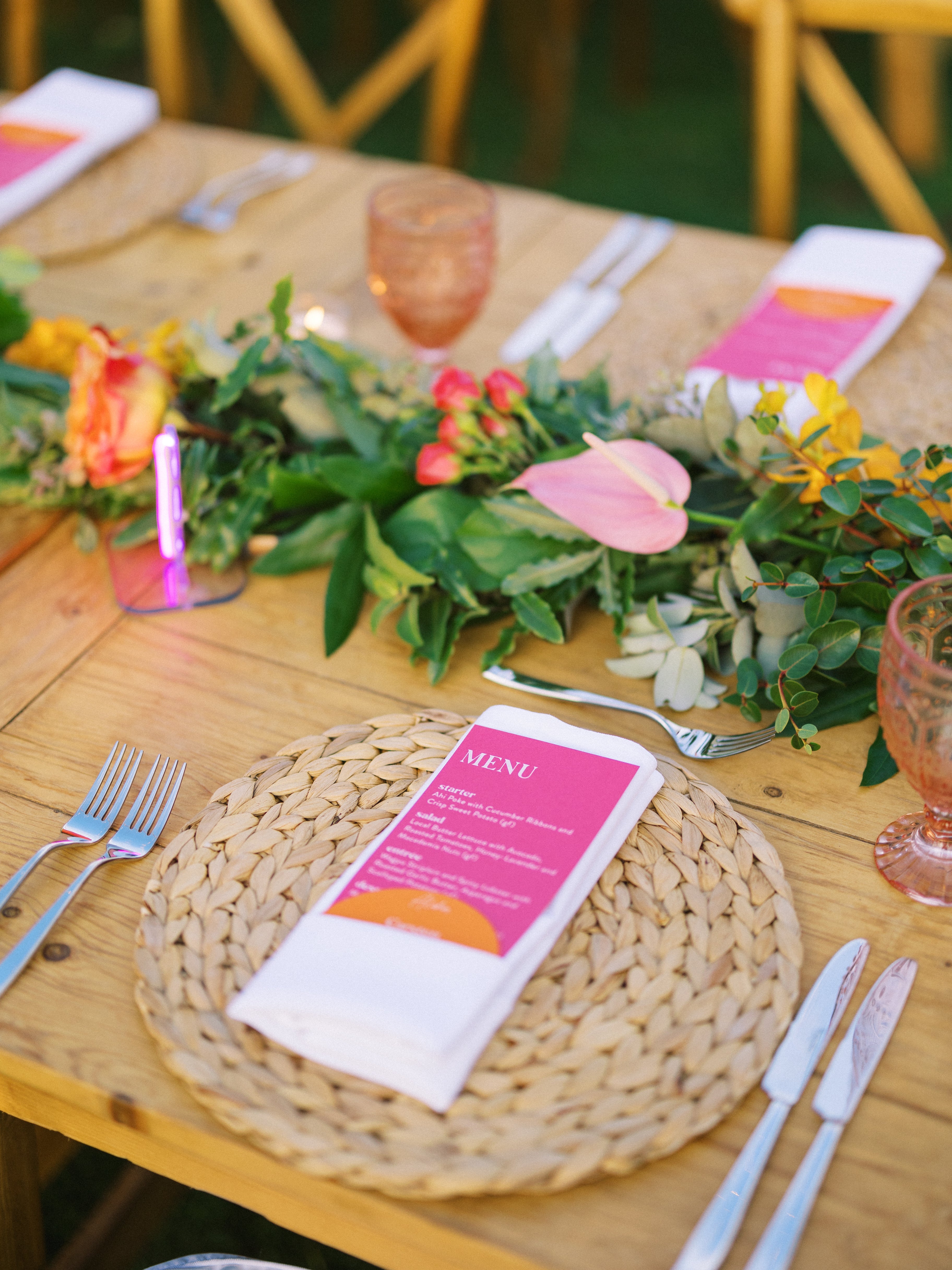 bright orange and pink wedding stationery on a woode dinner table