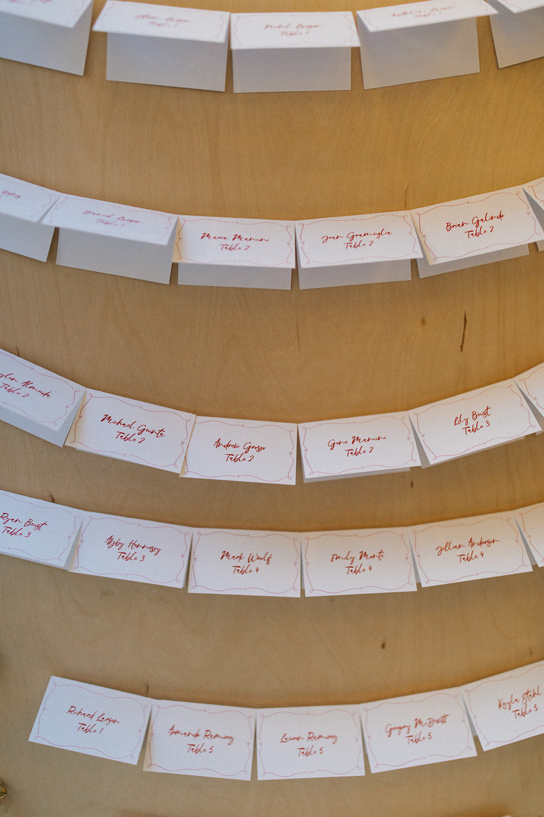 wedding escort cards displayed on a wooden stand 